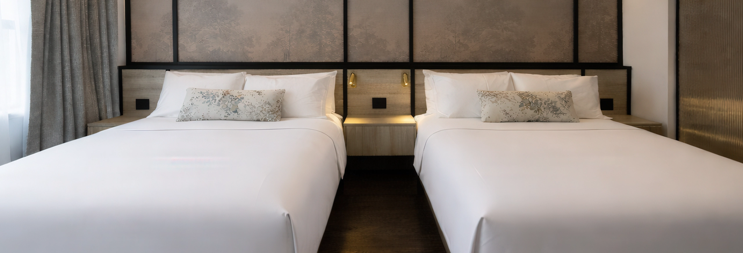 Luxury hotel suite at The Glenhill Hotel North York featuring two queen-size beds with premium white linens, high-end headboards, and elegant boutique finishes