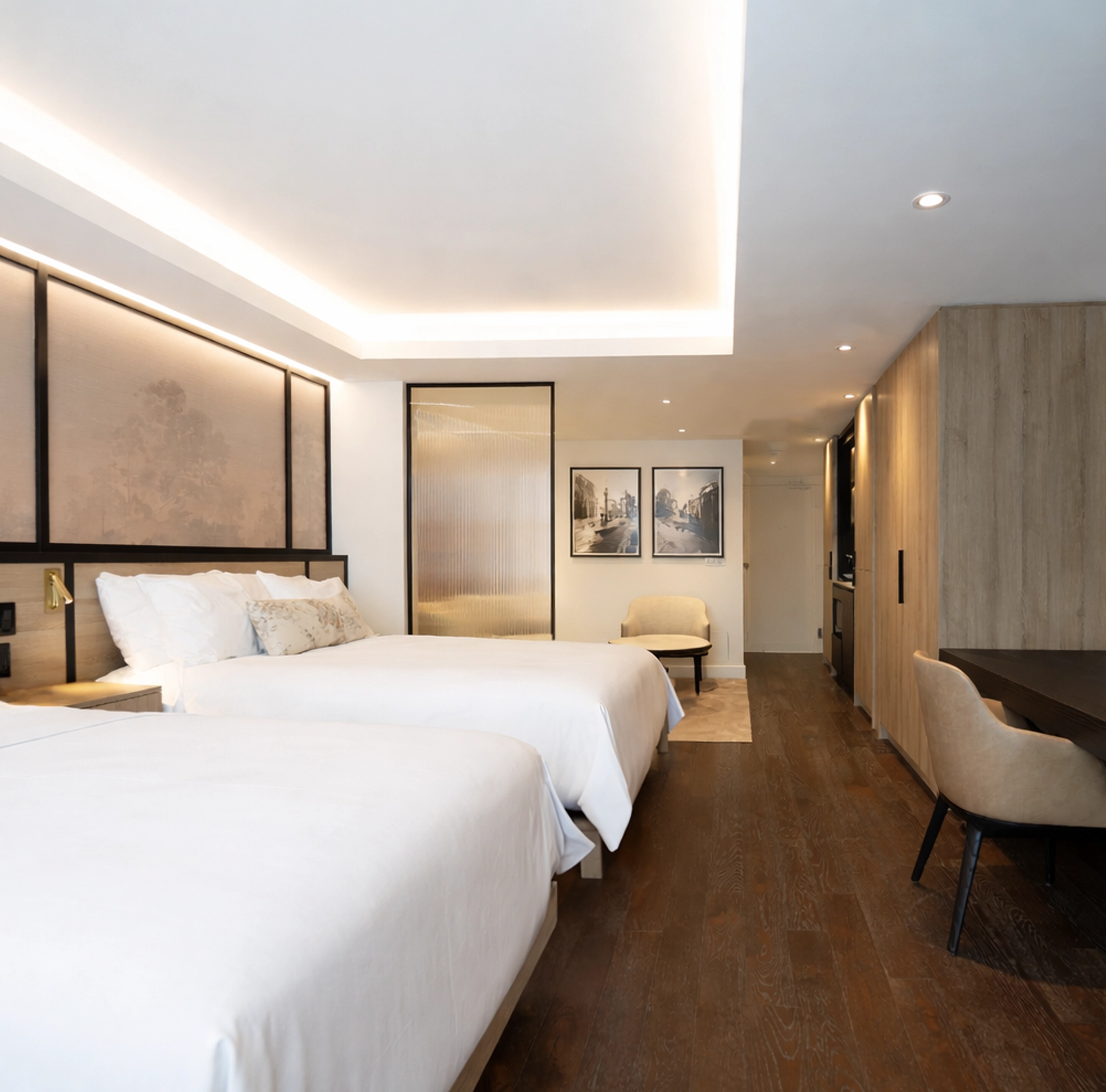 A view of a luxury hotel suite at The Glenhill Hotel North York featuring two queen-size beds with premium white linens, boutique finishes and high-end lighting throughout the living space.