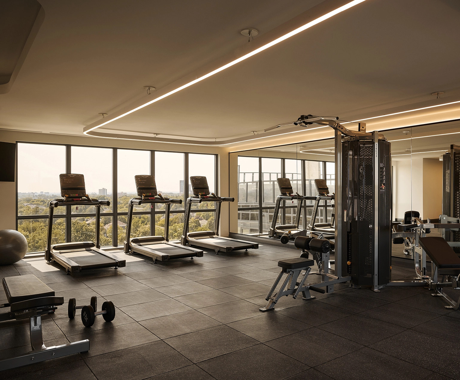 Bright and airy boutique hotel fitness centre with premium hardwood flooring and high-end exercise machines at Glenhill Hotel, North York