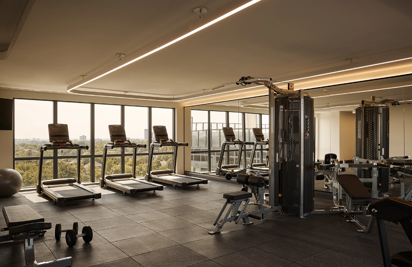 Bright and airy boutique hotel fitness centre with premium hardwood flooring and high-end exercise machines at Glenhill Hotel, North York
